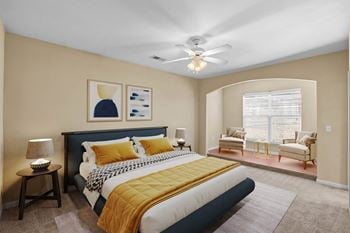 A bedroom with a large bed, ceiling fan, and library niche.